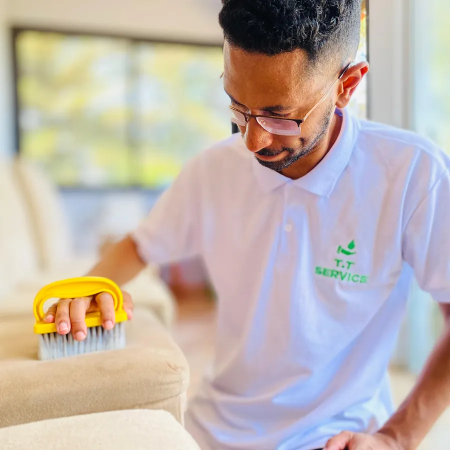 Técnico da T.T Service escovando o tecido de um sofá bege