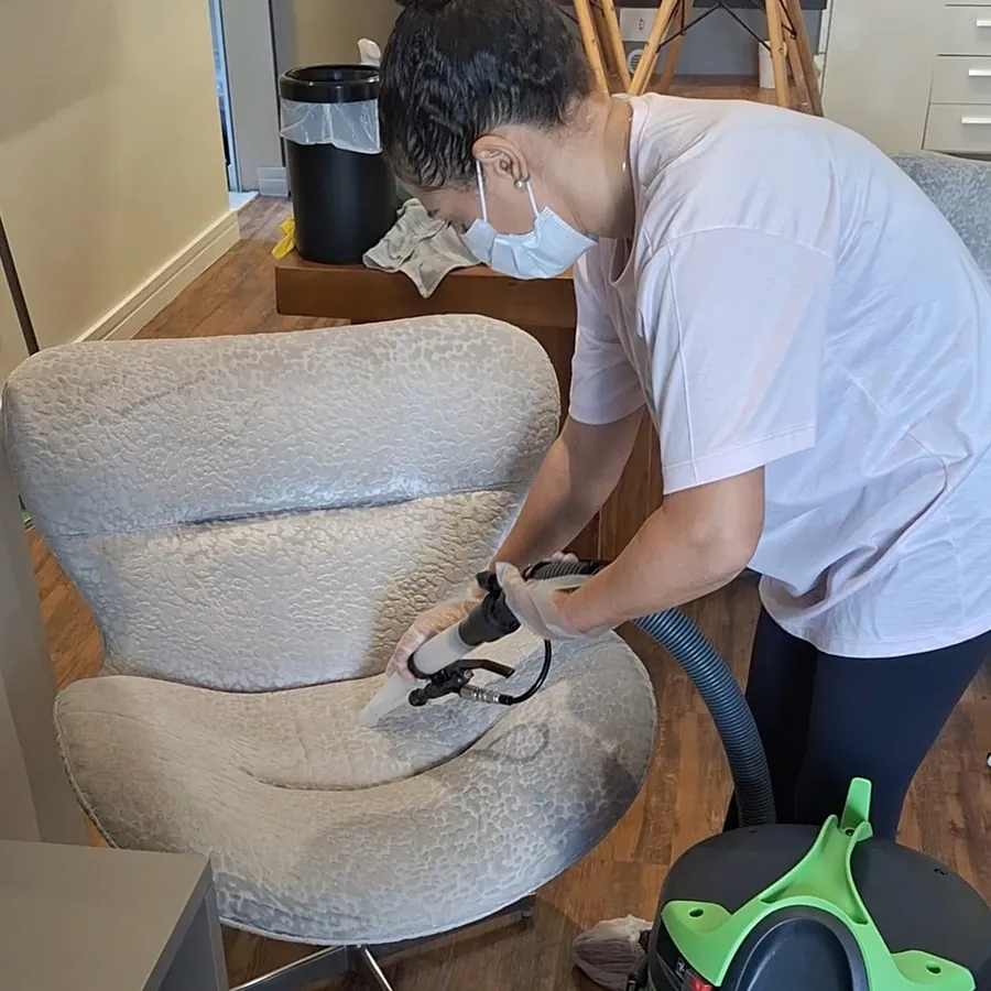 Técnica da T.T Service higienizando poltrona cinza com a extratora